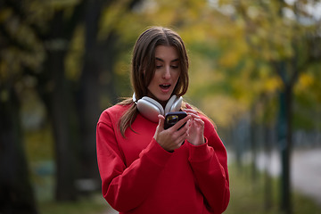 Image showing Sporty woman checks smartphone before doing some exercises listens music from a playlist