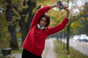 Image showing Athletic young woman taking a breath and relaxing after jogging and stretching. Woman Training and Workout Exercises On Street.