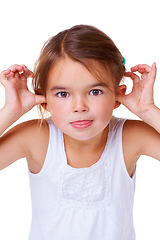 Image showing Portrait, children and having fun with a girl child in studio isolated on a white background for comedy. Comic, funny face or mock and an adorable young kid sticking her thumbs in her ears for humor