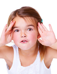 Image showing Portrait, surprise and peekaboo with a girl child in studio isolated on a white background for a playful game. Face, hands or wow and a cute young kid having fun with a gesture for comedy or humor