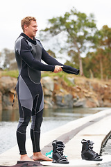 Image showing Sports, wetsuit and man by lake with wakeboard for surfing, exercise and recreation hobby outdoors. Fitness, extreme sport and person with board for water skiing for freedom, adventure and fun