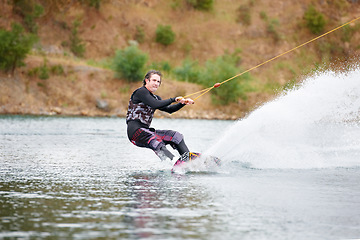 Image showing Spray, wakeboarding and adventure, man on lake with outdoor fun, fitness and wave splash. Balance, water sports and person on river with freedom, speed and energy for surfing challenge, ski and trick