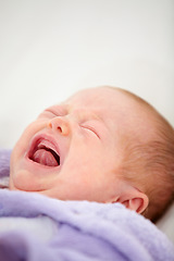 Image showing Sad, crying or tantrum with a baby on a bed closeup in a home for emotion, expression or child development. Face, tired or hungry with a newborn infant in the bedroom of an apartment for growth