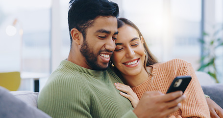 Image showing Couple, phone and smile in living room for social media, reading notification or scroll with online shopping app at home. Happy man, interracial woman and smartphone to search digital news on website