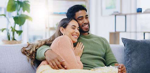 Image showing Love, hug and couple on watching tv on a sofa with popcorn for movie, film or streaming show at home. Relax, television and people embrace in a living room with cinema snack for comedy or series