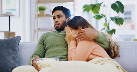 Image showing Fear, hug and couple watching tv on a sofa with popcorn for movie, film or streaming show at home. Wow, television and people embrace in living room with cinema snack for omg, horror or spooky series