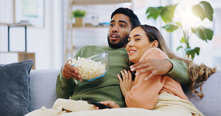 Image showing Fear, hug and couple watching tv with popcorn on a sofa for movie, film or streaming show in their home. Wow, television and people embrace in a living room with cinema snack for horror or series