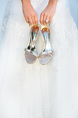 Image showing Hands, wedding and closeup of a bride with shoes and dress for luxury, elegant and romantic event. Zoom of woman with silver, fashion and bridal heels and garments marriage ceremony or celebration.