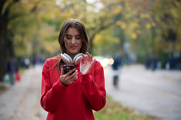 Image showing Sporty woman checks smartphone before doing some exercises listens music from a playlist