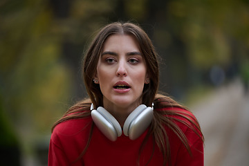 Image showing Athletic young woman taking a breath and relaxing after jogging and stretching. Woman Training and Workout Exercises On Street.