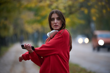 Image showing Athletic young woman taking a breath and relaxing after jogging and stretching. Woman Training and Workout Exercises On Street.