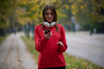 Image showing Sporty woman checks smartphone before doing some exercises listens music from a playlist