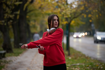 Image showing Athletic young woman taking a breath and relaxing after jogging and stretching. Woman Training and Workout Exercises On Street.