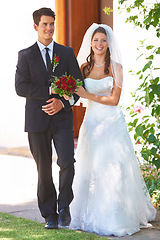 Image showing Happy couple, wedding and holding hands with roses for marriage, love or outdoor commitment together. Married bride and groom walking with smile and bouquet of flowers at bridal event or ceremony
