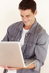 Image showing Man, laptop and smile in studio for remote work, elearning and search subscription for digital download on white background. Happy freelancer typing on computer to update blog, online shopping or web