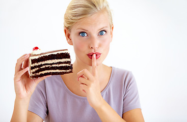 Image showing Secret, cake and young woman in a studio cheating on healthy, wellness or weight loss diet. Yummy, sweet and female person from Australia eating a chocolate dessert isolated by white background.