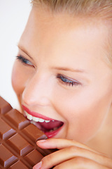 Image showing Studio face, woman and eating chocolate slab bar, delicious snack or unhealthy junk food, dessert or sugar candy. Wellness craving, beauty skin and person bite sweets isolated on white background