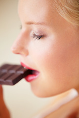 Image showing Relax woman face, eating and bite chocolate bar, tasty cocoa snack or unhealthy junk food for wellness, stress relief or craving. Head profile, antioxidant product benefits and girl enjoy cacao slab