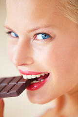 Image showing Portrait, eating or happy woman bite chocolate bar, snack or junk food for wellness, stress relief or craving. Face headshot, delight or girl taste cacao slab, antioxidant benefits or diet cheat meal