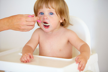 Image showing Hand, baby and eating food or portrait for healthy dinner or childhood development, hungry on spoon. Person, feeding chair and kid face for lunch time or nutrition vitamins, breakfast or parent care