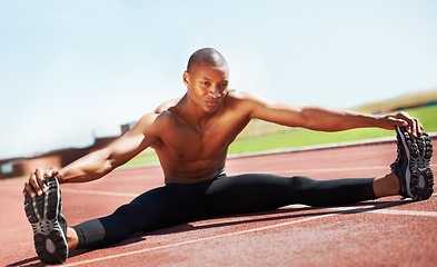 Image showing Man, athlete and stretching legs on floor, outdoors and fitness for health, sports and performance. Black male person, ready and warmup on track, workout and commitment in training, start and cardio