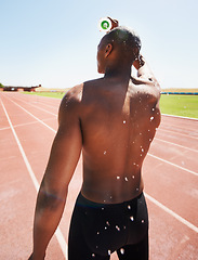 Image showing Man, bottle and pouring water or fitness, outdoors and liquid for refreshment, hydration and cool down. Black male person, back and athlete or splash, hot and exhausted from workout, training or race