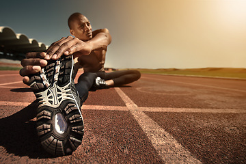 Image showing Man, shoes and stretching leg on ground, sunset and fitness for health, sports and performance. Black male person, athlete and warmup on track, workout and commitment or ready, train and outdoors