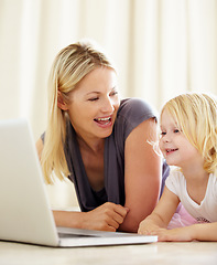 Image showing Online, learning and mom with girl on laptop with development, games and education in home. House, computer and mother with child in living room on website for growth and knowledge on internet