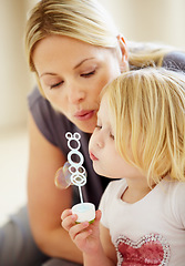 Image showing Blowing, bubbles and games with mom and child together in home playing with toys for fun. Playful, mother and daughter with liquid, soap and bonding on holiday, vacation or relax on weekend with love