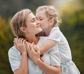 Image showing Nature, hugging and child kissing her mother in an outdoor garden for bonding together. Happy, smile and girl kid embracing her young mom from Canada with love and care in the park or field.