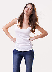 Image showing Portrait, fashion or casual and a woman in studio on a white background with her hands on her hips. Trendy, style and clothes with a confident young female model in a denim jeans and tank top outfit