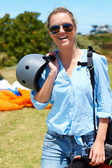 Image showing Woman, parachute and field happy for skydiving summer, fearless or outdoor adventure. Female person, smile and portrait or helmet protection for extreme sports or danger, action or brave jump gear