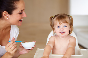 Image showing Portrait, family and a mother feeding her baby breakfast in the morning while in a home together for development. Children, food and a girl toddler eating with a woman parent in an apartment kitchen