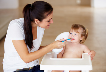 Image showing Family, food and a mother feeding her baby breakfast in the morning while in a home together for development. Children, growth and a girl toddler eating with her woman parent in an apartment kitchen