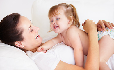 Image showing Baby, mother and laughing or hug on sofa with playing, relax and parenting in living room of home with security. Family, woman and girl child with happiness on couch in lounge for development or love