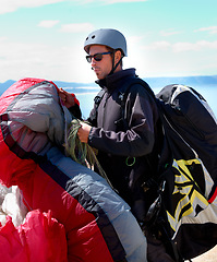 Image showing Paragliding, parachute or man in nature for sport, preparation or helmet to exercise for health support. Athlete, training or fitness for outdoor wellness, backpack or safety equipment in countryside