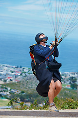 Image showing Man, parachute and paragliding launch in air in nature, healthy adventure and fun in extreme sport. Athlete, take off or fearless for outdoor fitness for wellness, helmet or safety gear by blue sky