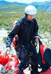 Image showing Sports, parachute and man in nature with equipment, safety preparation and helmet in paragliding exercise. Athlete, training or gear for outdoor adventure, backpack or happy wellness in countryside