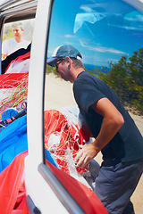 Image showing Extreme sports, adventure and a parachute in a car with a man unpacking equipment for an adrenaline activity. Travel, skydiving and getting ready for a jump outdoor in the dessert for an experience