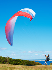Image showing Man, parachute and paragliding launch in nature with safety training, healthy adventure and extreme sport. Person, strings and flying skill for outdoor fitness with helmet and blue sky for wellness