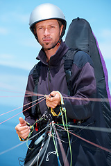 Image showing Paragliding, parachute and man with preparation in nature, strings and exercise for health support. Athlete, training or fitness for outdoor with safety harness, helmet or equipment in countryside