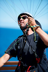 Image showing Man, parachute and paragliding launch in air in nature, exercise and healthy adventure fof extreme sport. Person, glide or fearless in outdoor fitness for wellness, helmet or safety gear by blue sky