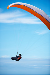Image showing Man, paragliding and blue sky adventure parachute in clouds for explore city, outdoor courage or fearless athlete. Male person, safety equipment for landing flying in nature sport, activity in wind