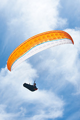 Image showing Man, parachute and paragliding in blue sky for flight, freedom and courage with extreme sport. Athlete, glide and fearless in outdoor fitness for adventure, health and sports by ocean with mountain