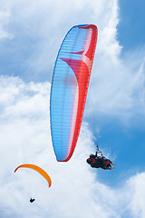 Image showing Person, parachute and paragliding in blue sky for flight, stunt and courage with extreme sport. Athlete, glide and fearless in outdoor fitness for adventure, health and sports by ocean with mountain