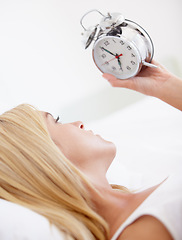 Image showing Woman, holding and alarm clock for wake up in bedroom for early, morning and sleep in house. Female person, looking and time with upset, serious and expression for day with noise, alert and sound