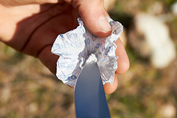 Image showing Person, hand and knife with cocaine, drugs or sample for recreation, addiction or habit outdoor. Man, product and packaging on grass in nature with weapon, illegal or unhealthy lifestyle or substance