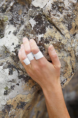 Image showing Person, mountain and rock climbing or finger tape on hand for exercise injury, sports grip on nature cliff. Athlete, boulder and hanging for explore peak practice for brave adventure, risk or strong