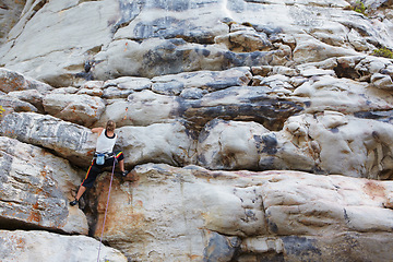 Image showing Woman, rock climbing and mountain or rope adventure or grip strength, stone cliff or sports challenge. Female person, boulder hill and gear for outdoor peak explore for healthy fear, risk or danger