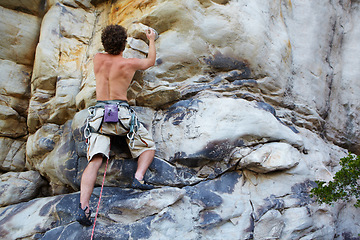 Image showing Man, rock climbing and rope hanging on mountain boulder for challenge, risk performance on stone. Male person, exercise and outdoor cardio gear or courage as fearless athlete, brave danger on cliff